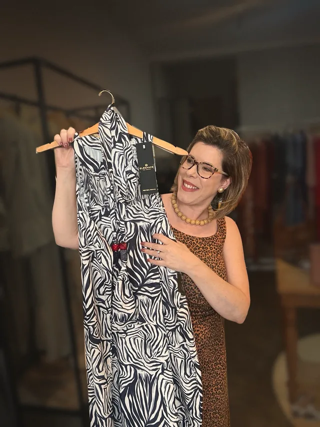 Branca Pedroso segurando um vestido de estampa de zebra com a etiqueta da marca